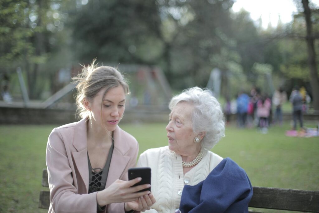 A woman sits with old lady and talk to her