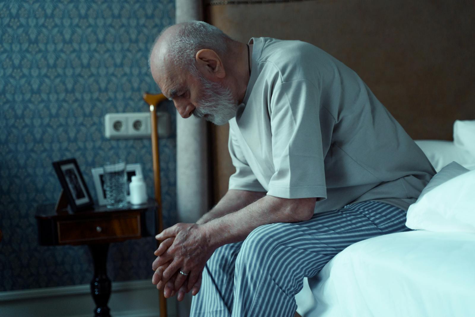 Sad elderly man sitting on bed