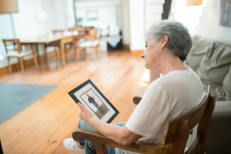 Sad elderly woman looking at a photo in nursing home